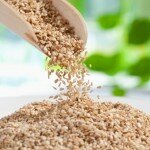 Seasame seeds pouring from wooden scoop, close up